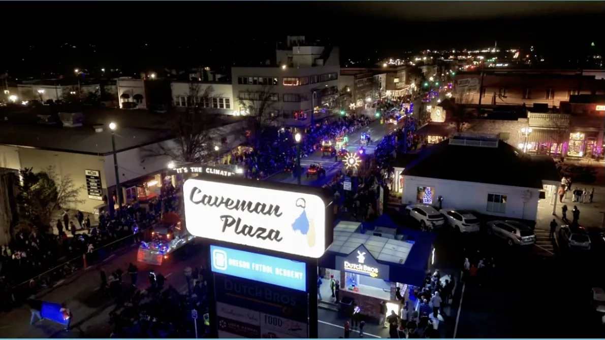 Night drone photo of Caveman Plaza and a holiday parade in downtown Grants Pass