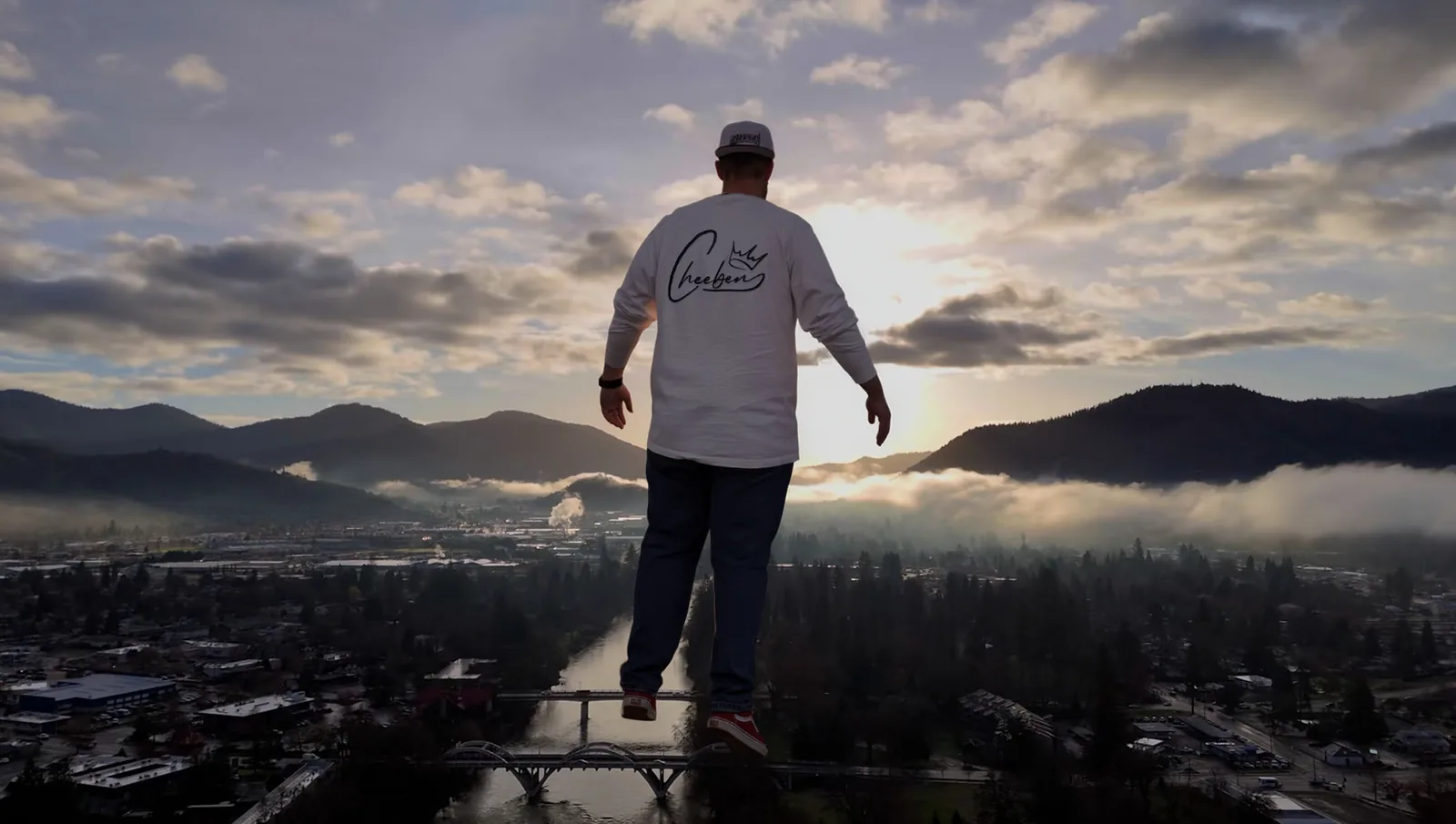 Creative composite of Steven 'Cheeben' Buchanan standing over the Rogue River and downtown Grants Pass, Oregon at sunrise